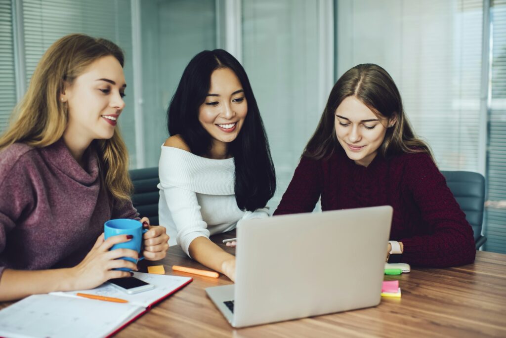 3 junge Frauen kaufen zusammen in einem Online-Shop ein.